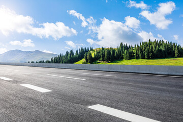 Empty asphalt road and green mountain nature scenery under blue sky