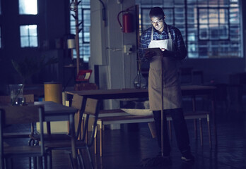 Aufkleber - Connected even while doing some chores. Shot of a young man working late on a digital tablet in his coffee shop.