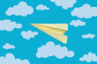 On a blue background there are clouds and one yellow paper plane, origami. Pattern, template, wallpaper.