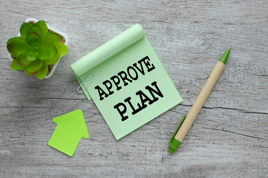green sticker on a gray wooden background. sticker text approve plan