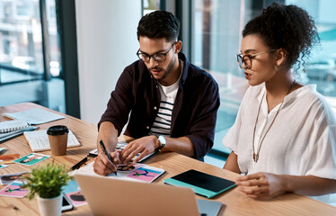 Poster - Lets mark this one so we dont forget. Cropped shot of two young businesspeople sitting together and having a meeting over polaroids in the office.