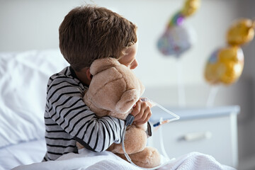 Child hugging teddy bear at hospital