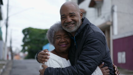 Wall Mural - An adult son embracing elderly mother family love affection outside