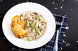 on a white plate chicken fricassee with mushrooms, with fried potatoes, on a black isolated background