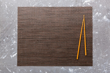 Wall Mural - Two chopsticks and bamboo mat on cement background. Top view, copy space