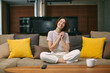 © Georgii - Touched smiling young girl feel happy from tender moment of romantic movie, sitting on comfortable couch at home