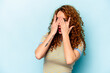 © Asier - Young ginger caucasian woman isolated on blue background blink through fingers frightened and nervous.