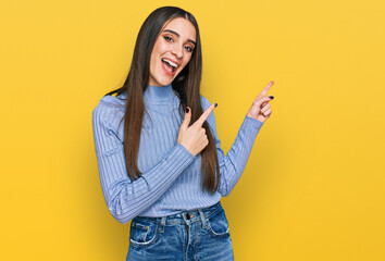 Wall Mural - Young beautiful woman wearing casual winter sweater smiling and looking at the camera pointing with two hands and fingers to the side.