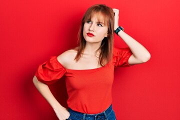 Canvas Print - Redhead young woman wearing casual red t shirt confuse and wondering about question. uncertain with doubt, thinking with hand on head. pensive concept.