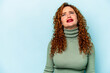 © Asier - Young ginger caucasian woman isolated on blue background shouting very angry, rage concept, frustrated.