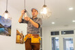 © Angelov - An electrician is installing spotlights on the ceiling
