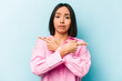 © Asier - Young hispanic woman isolated on blue background points sideways, is trying to choose between two options.