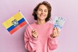 Young brunette woman holding colombia flag and colombian pesos banknotes smiling with a happy and cool smile on face. showing teeth.