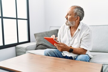 Wall Mural - Senior grey-haired man smiling confident using touchpad at home