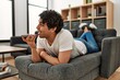 © Krakenimages.com - Young hispanic man talking on the smartphone lying on the sofa at home.