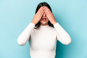 Wall Mural - Young caucasian woman isolated on blue background having fun covering half of face with palm.