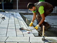 Construction Worker Arranging Paving Stones On Sidewalk