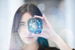 © Westend61 - Young businesswoman looking through open camera lens at office