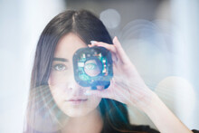 Young Businesswoman Looking Through Open Camera Lens At Office