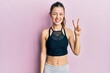 © Krakenimages.com - Young brunette woman wearing sportswear smiling with happy face winking at the camera doing victory sign. number two.