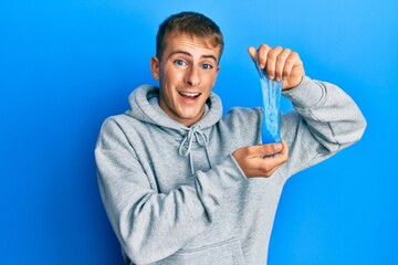 Wall Mural - Young caucasian man holding slime celebrating crazy and amazed for success with open eyes screaming excited.