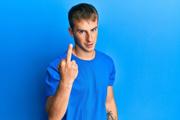 Poster - Young caucasian man wearing casual blue t shirt showing middle finger, impolite and rude fuck off expression