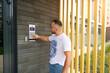 A young man stands at the building of a residential building and dials the code from the intercom door. Call the intercom with video communication. New modern doorphone