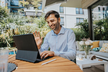 Smiling businessman waving on video call over tablet PC at back yard