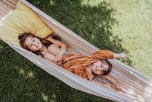 Smiling Sister And Brother Lying In Hammock At Back Yard