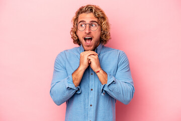 Wall Mural - Young caucasian man isolated on pink background keeps hands under chin, is looking happily aside.