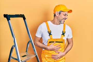 Poster - Handsome middle age man with grey hair holding ladder with hand on stomach because nausea, painful disease feeling unwell. ache concept.