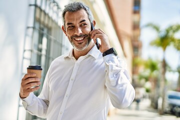 Sticker - Middle age grey-haired man talking on the smartphone drinking coffee at the city.