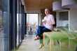 © Westend61 - Woman holding coffee cup sitting on table at home