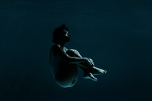 Young Woman In Fetal Position Swimming Underwater