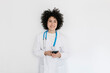 © Westend61 - Smiling doctor holding mobile phone standing in front of white wall