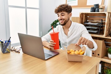 Wall Mural - Young arab man using laptop having lunch at office