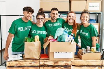 Group of young volunteers smiing happy looking to the camera standing at charity center.