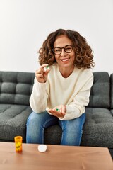 Wall Mural - Middle age hispanic woman smiling confident taking pills at home