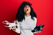African american woman with afro hair using drone with remote control angry and mad screaming frustrated and furious, shouting with anger looking up.