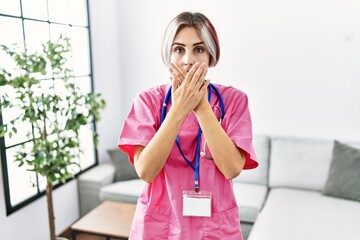 Sticker - Young beautiful woman wearing doctor uniform and stethoscope shocked covering mouth with hands for mistake. secret concept.