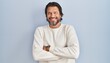 © Krakenimages.com - Handsome middle age man wearing casual sweater over blue background happy face smiling with crossed arms looking at the camera. positive person.
