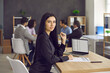 © Studio Romantic - Portrait of serious confident business woman sitting at office desk with laptop and papers. HR manager evaluating CVs and resumes. Young female employee working on notebook computer