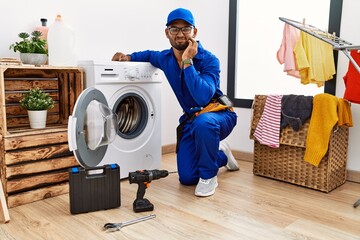 Canvas Print - Young indian technician working on washing machine touching mouth with hand with painful expression because of toothache or dental illness on teeth. dentist concept.