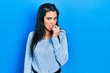 © Krakenimages.com - Young hispanic girl wearing casual clothes looking stressed and nervous with hands on mouth biting nails. anxiety problem.