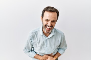 Middle age hispanic man with beard standing over isolated background smiling and laughing hard out loud because funny crazy joke with hands on body.