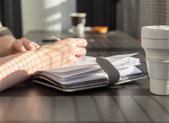 Poster - Woman hands closeup writing with pen in notebook or planner, taking notes in cafe with takeaway, silicon cup. High quality photo