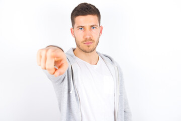 Cheerful young caucasian man wearing casual clothes over white background indicates happily at you, chooses to compete, has positive expression, makes choice.