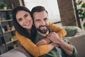 Sticker - Portrait of attractive cheerful couple hugging spending vacation sitting on sofa having fun at home house flat indoors