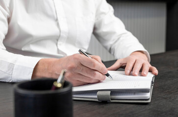 Poster - Hands taking notes in planner notebook. Employee at desk, writing plans. Business concept. High quality photo