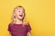 © Андрей Жерновой - Close-up portrait of a cute attractive cheerful excited girl. Cute sweet smiling child in a pink striped t-shirt. Blonde girl 5 years old on a bright yellow background with a place for text